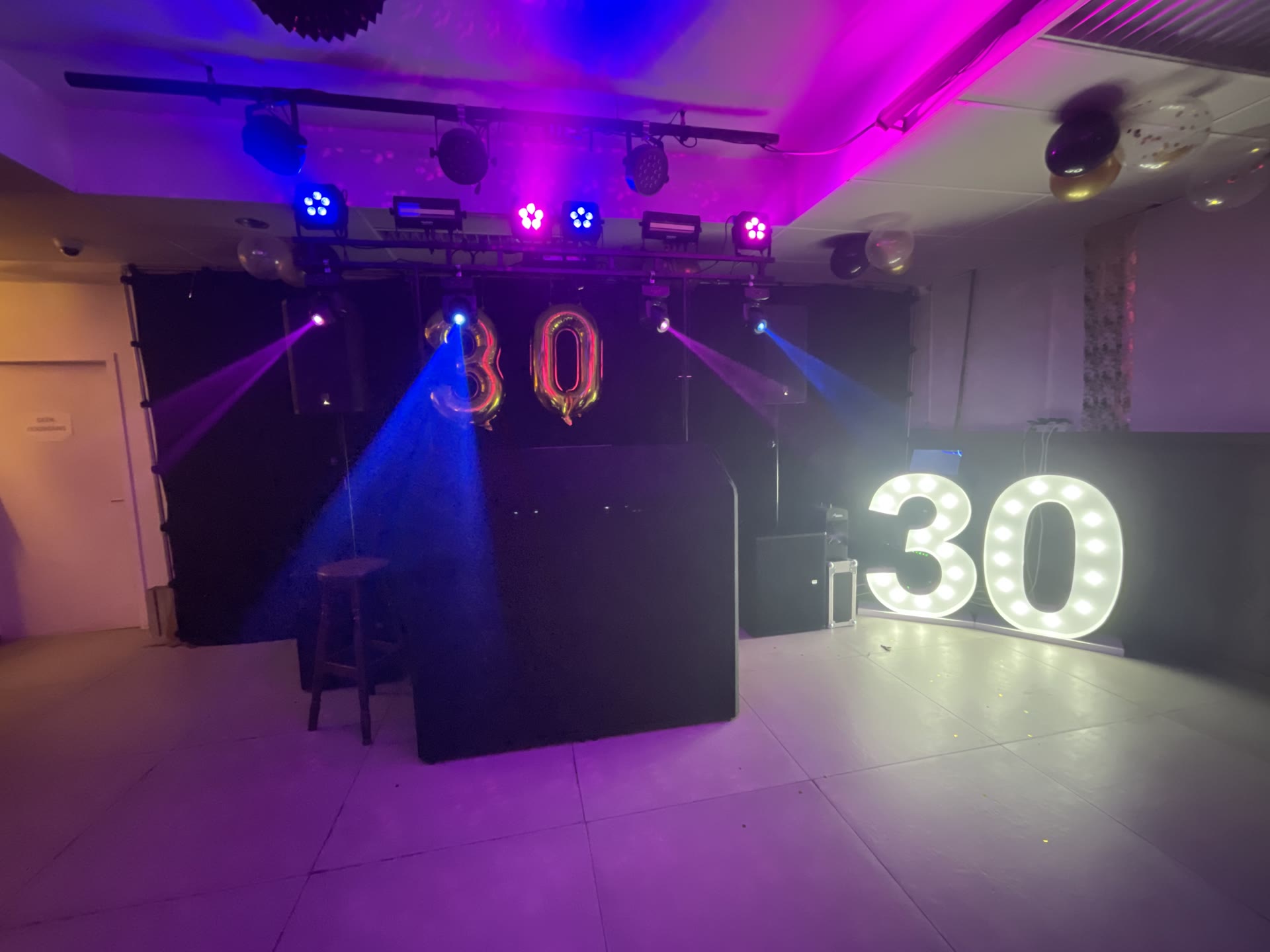 Verjaardagsfeest met verlichte cijfers 30, een DJ-booth en moving heads