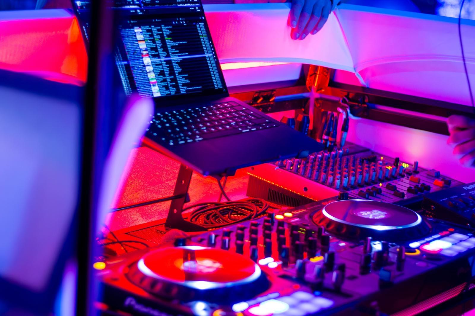 DJ-set met laptop, mixer en draaitafels in paars en rood licht