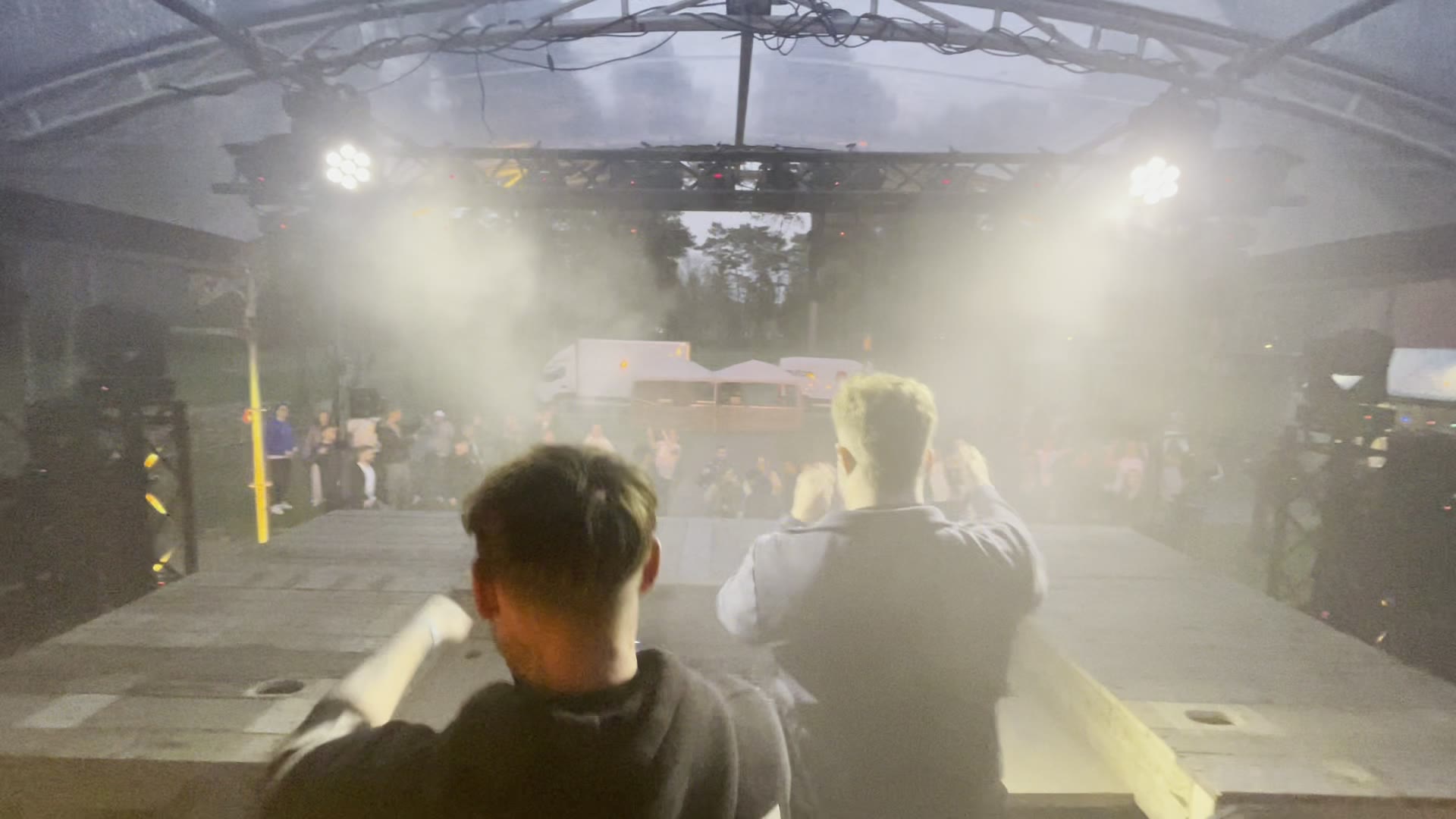 Festivalpodium met truss en rook, gezien vanachter de draaitafels