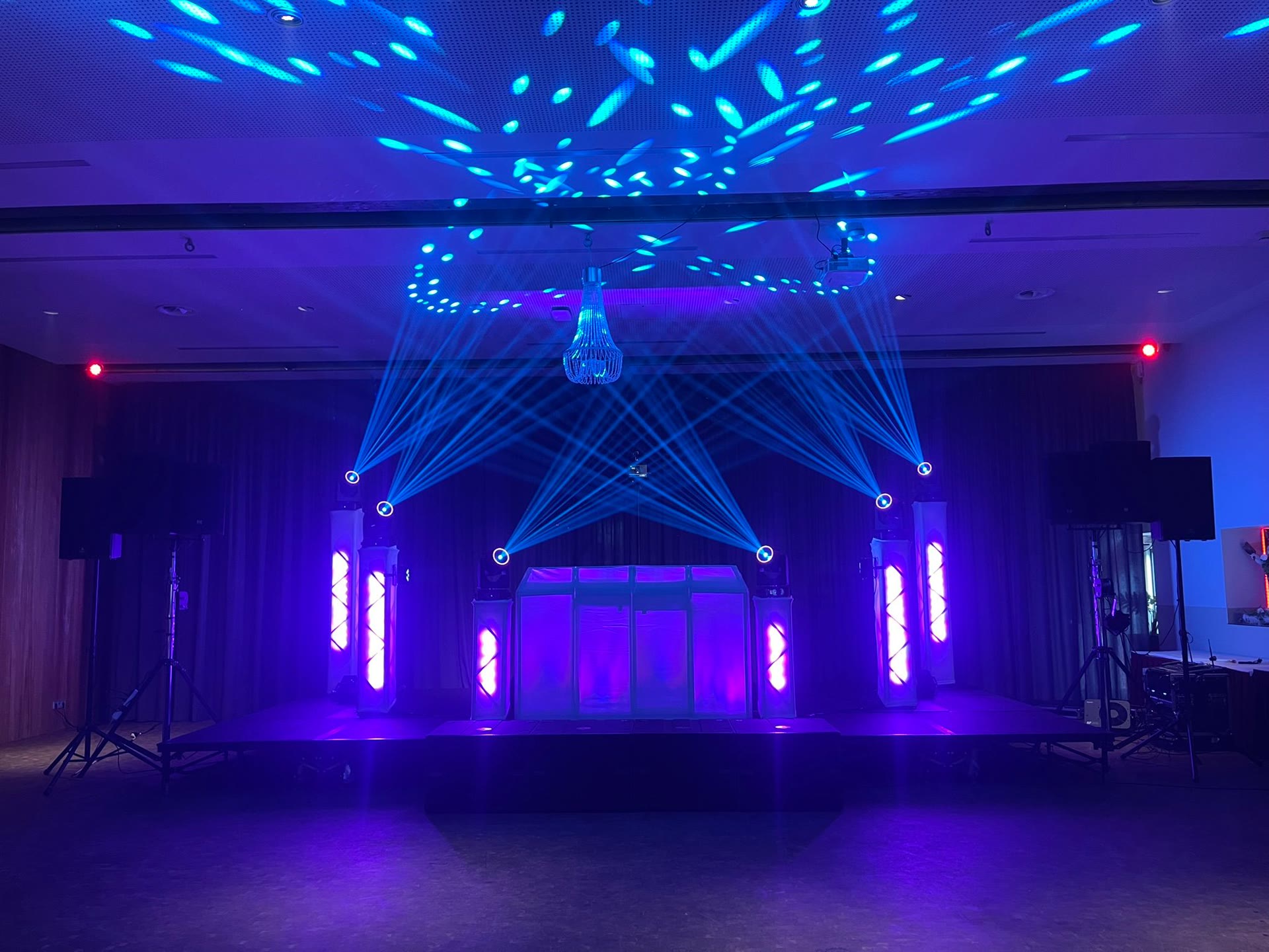 Zaal met roze lasers en een witte DJ-booth
