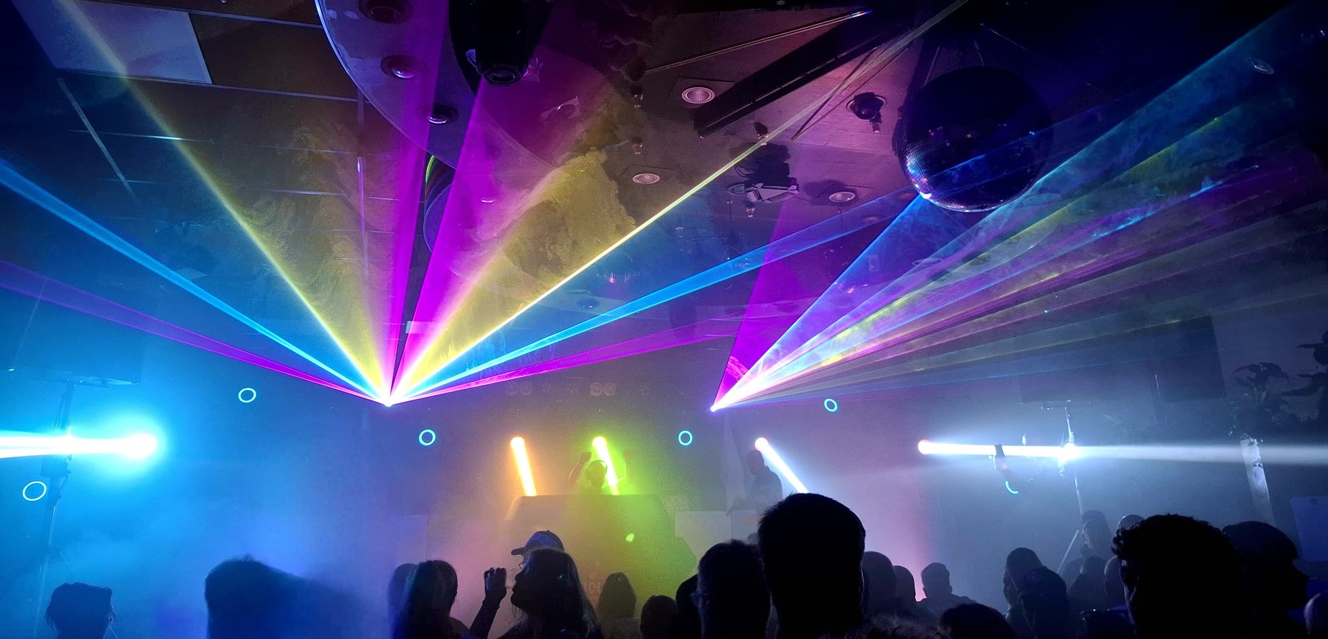 Paarse en groene lasers boven een dansende menigte