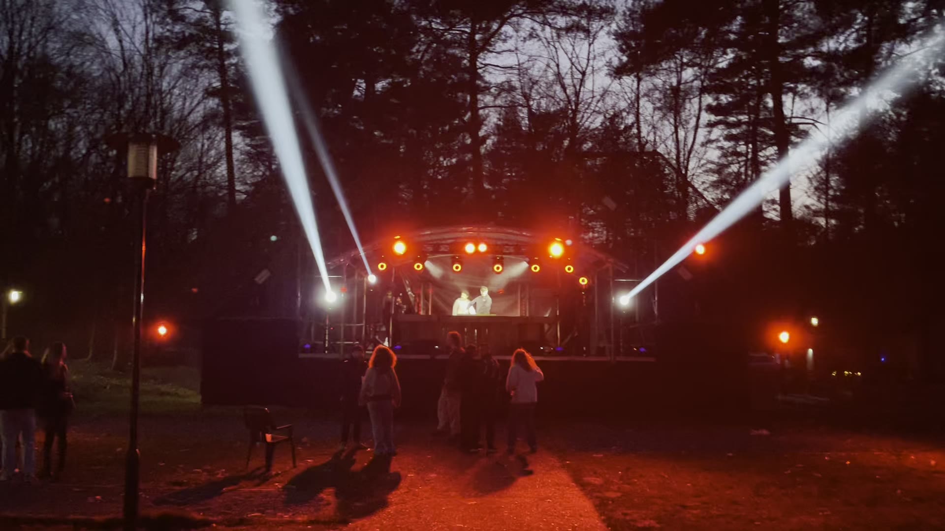 Buitenpodium met truss en lichtstralen tussen de bomen