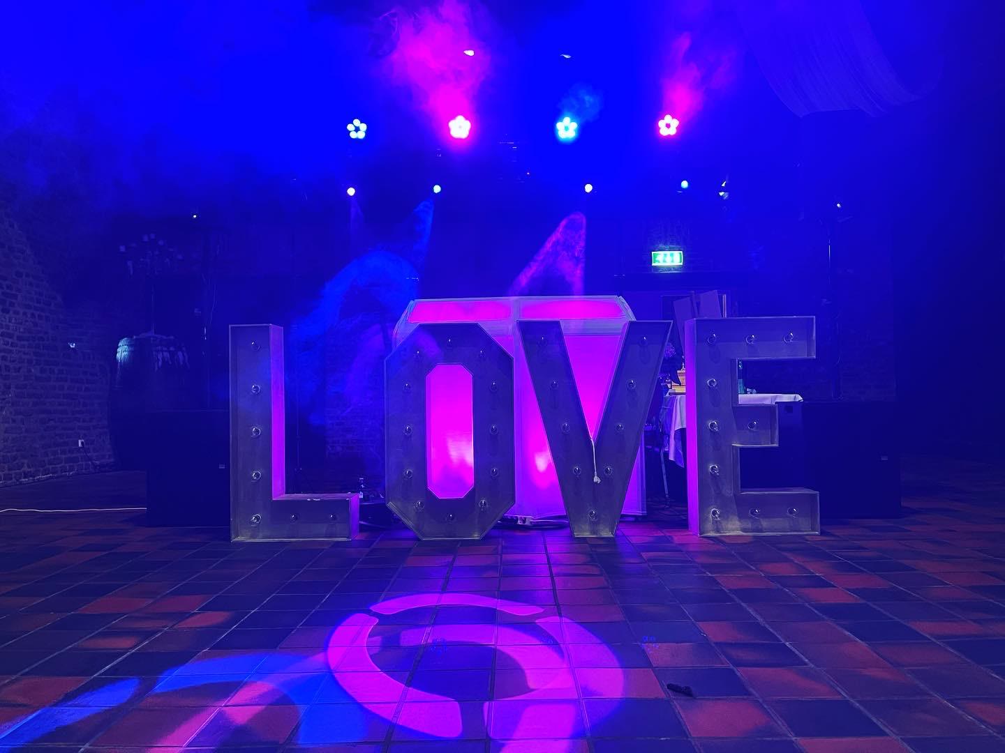Verlichte letters LOVE op de dansvloer van een bruiloft